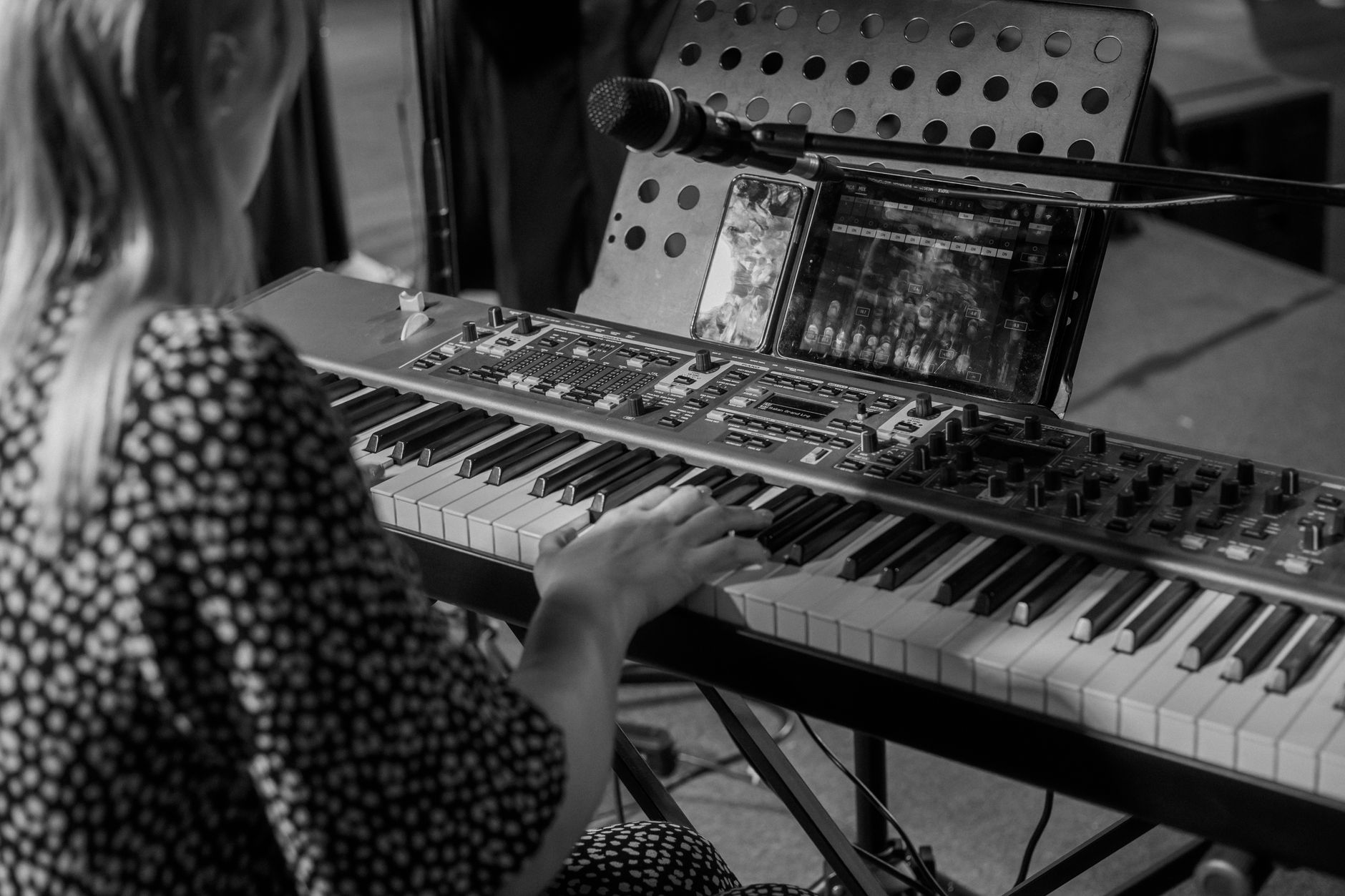 Multiinstrumentista concentrado produciendo un álbum independiente en su estudio casero con guitarra, teclado y equipo de grabación.
