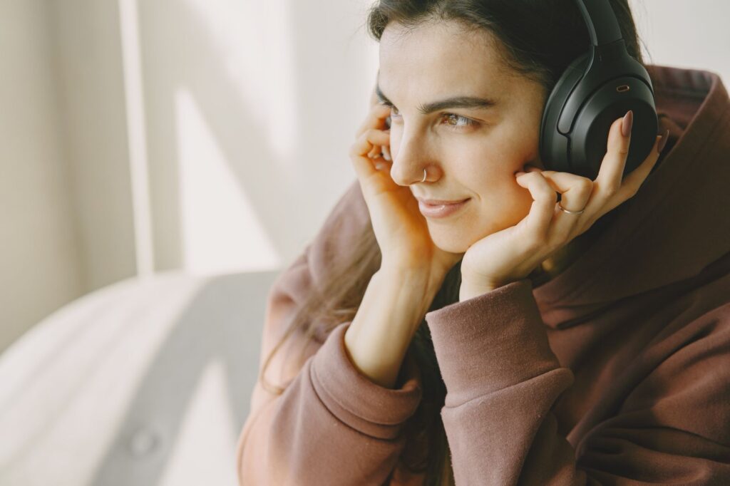 Persona escuchando música de alta calidad con audífonos profesionales en un entorno de trabajo creativo, inmersa en la experiencia sonora.
