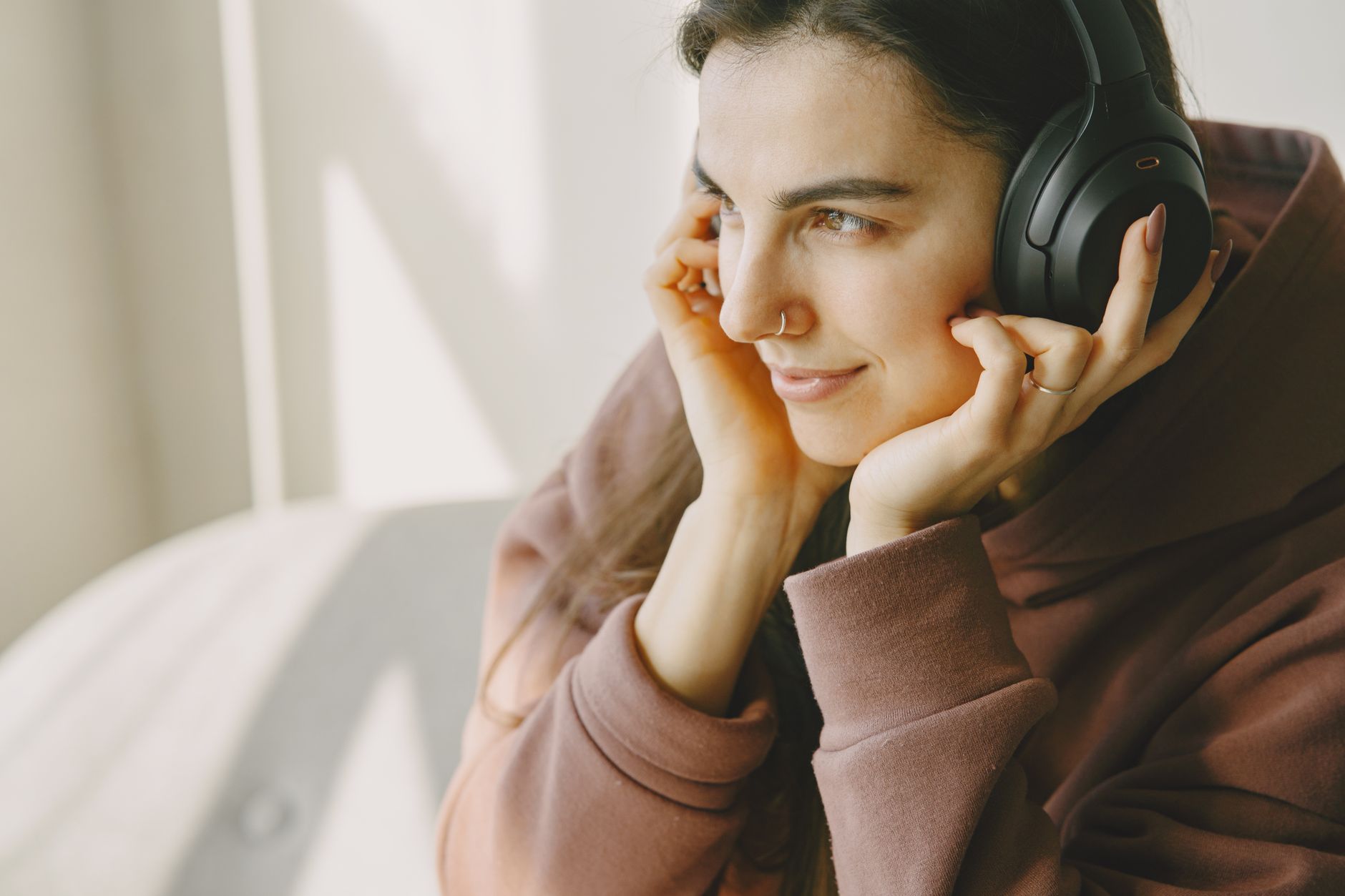 Persona escuchando música de alta calidad con audífonos profesionales en un entorno de trabajo creativo, inmersa en la experiencia sonora.