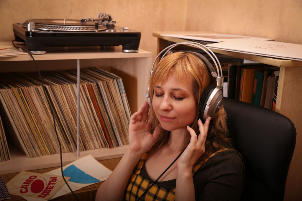 Persona escuchando música con audífonos, con tocadiscos y equipo de audio digital en el fondo, simbolizando la fusión de tecnologías.