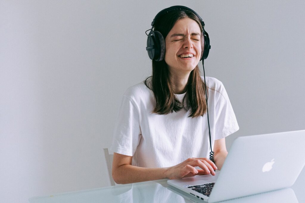 Persona descubriendo nuevos artistas en Spotify, usando audífonos y una laptop en un ambiente relajado.