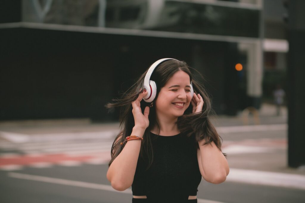 Persona escuchando música alternativa con audífonos mientras camina por un callejón urbano con arte callejero, descubriendo nuevas playlists.